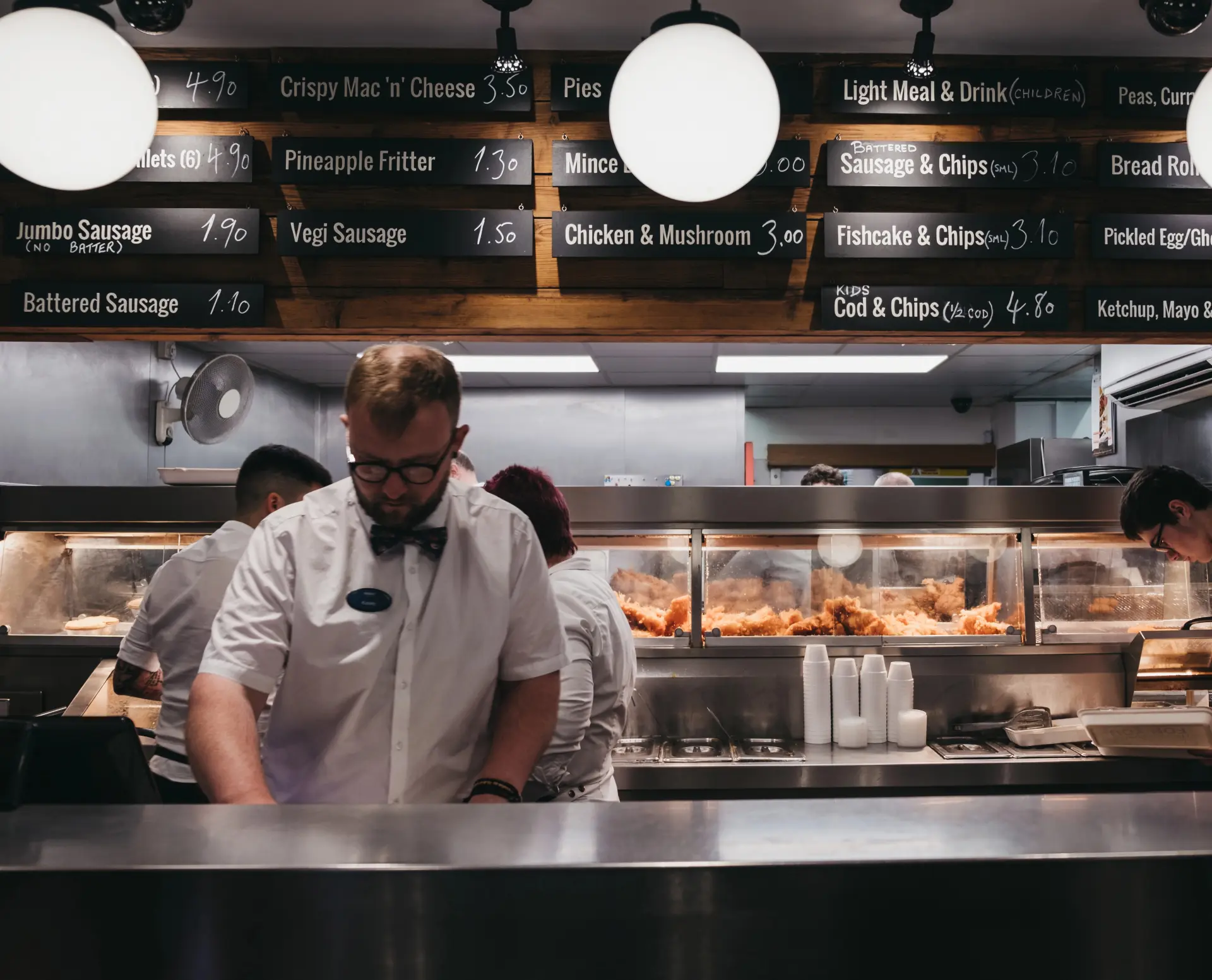 A busy restaurant scene, showing cooks and staff behind a counter preparing food at a diner.